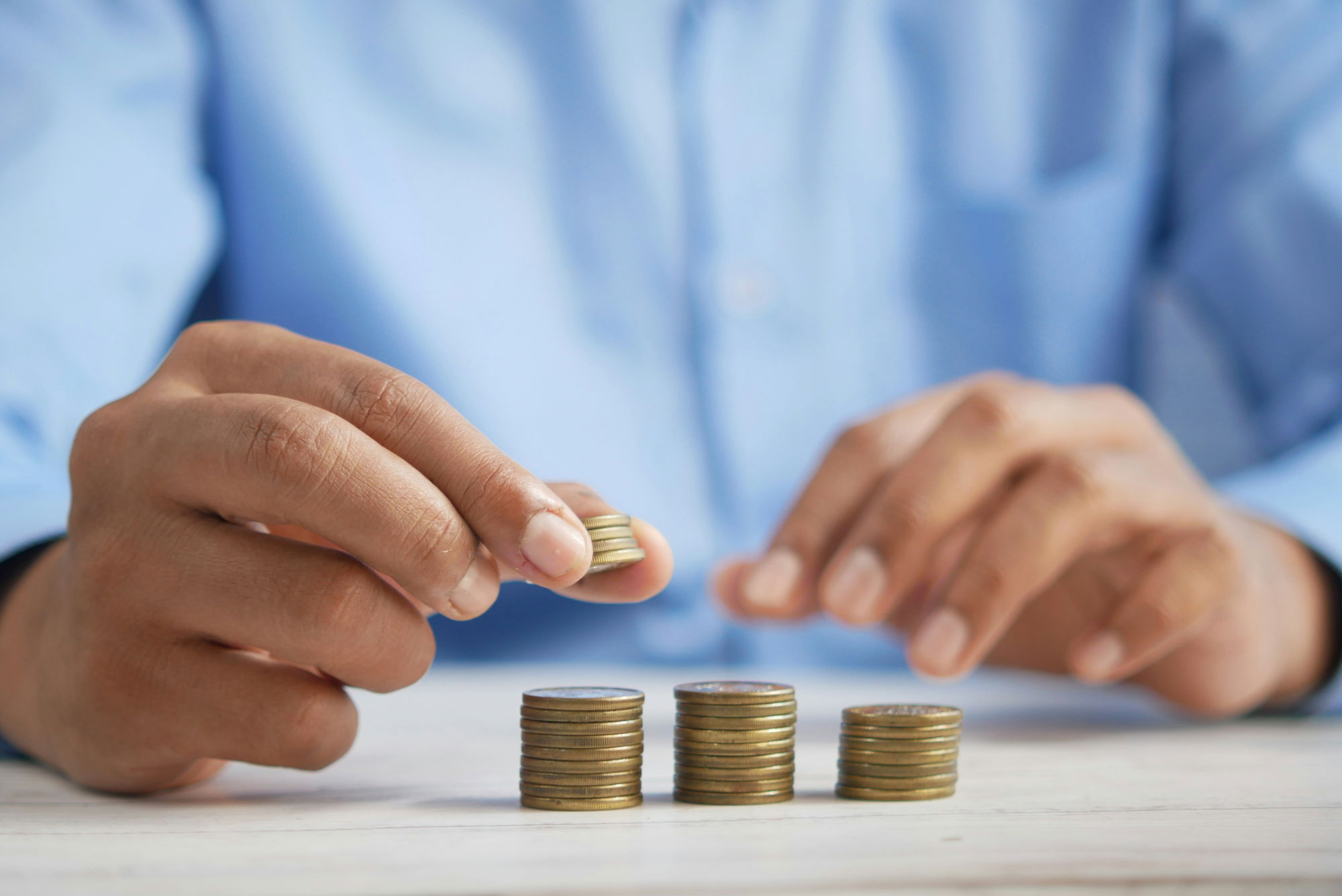 a-person-stacking-coins-on-top-of-a-table.jpg a person stacking coins on top of a table